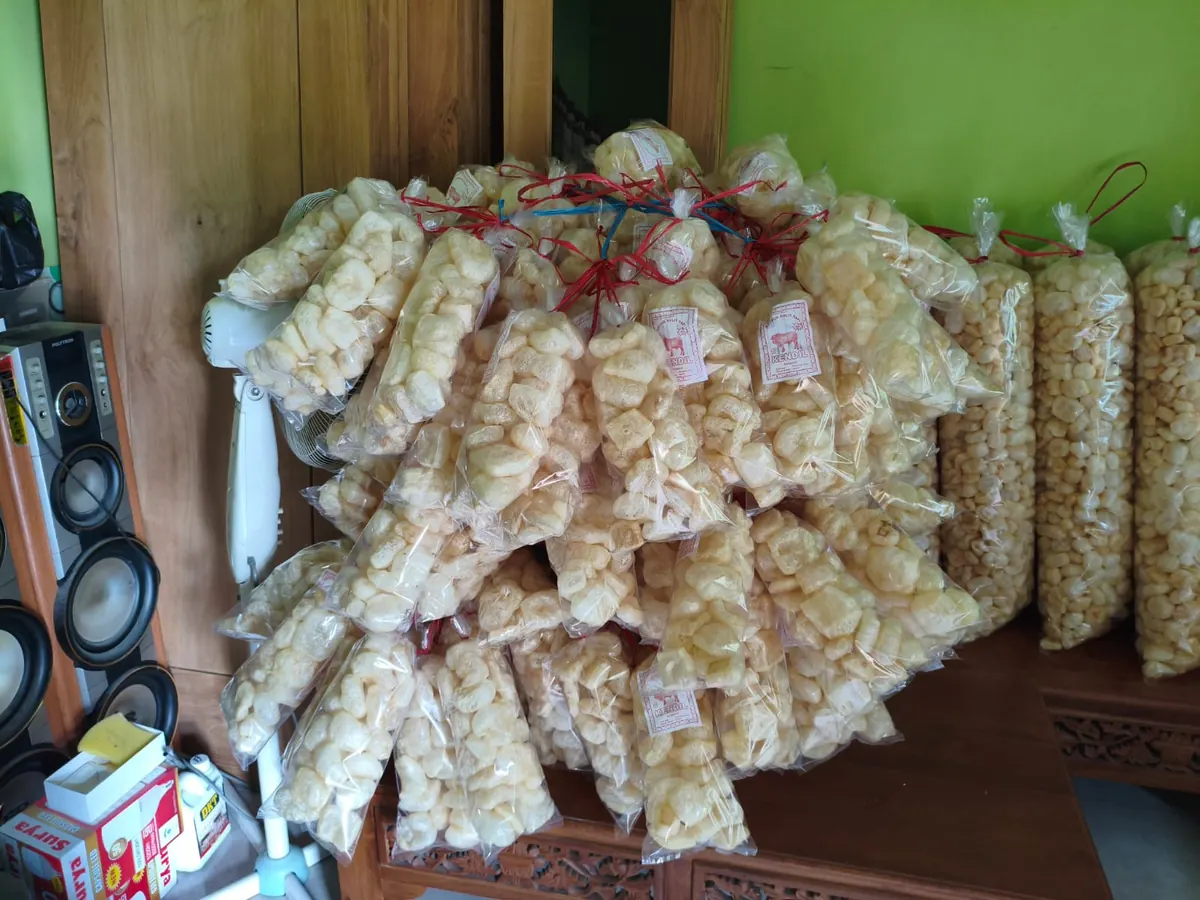Tumpukan kemasan kerupuk kulit sapi di samping dinding hijau